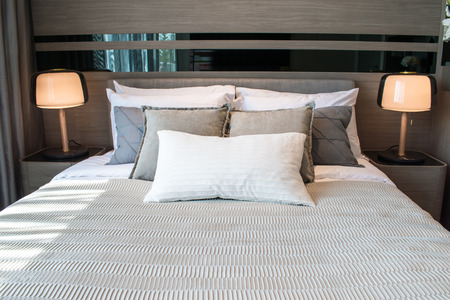 Modern bedroom interior design with many pillows and two lights.