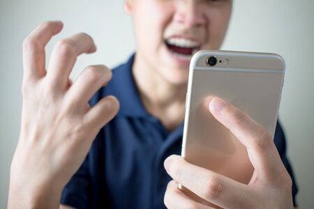 The young man felt angry from the smartphone with problems or errors.の写真素材