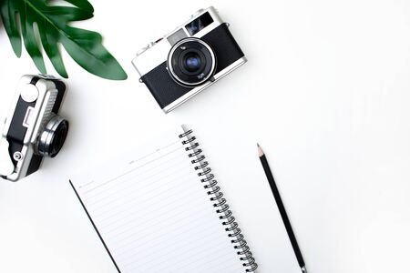 Top view of film camera with notebook, pencil and leaves. Isolated white background.の写真素材