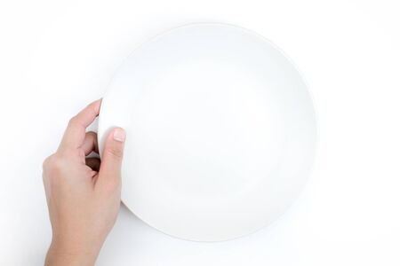 Top view, hand holding a white plate on a white background, Close up. Isolated background.の写真素材