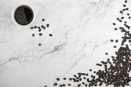 Top view of brown coffee beans with coffee on a marble background with copy space.の写真素材
