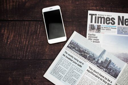 Newspapers and smartphones on a wooden table with a top view.