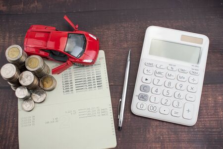 Coins stacked in columns on a bank book, car finance. Financial and banking concepts.の写真素材