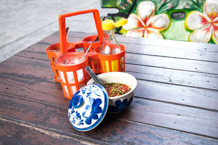 Sugar, fish sauce, vinegar, cayenne pepper, seasoning, Thai noodles on old wooden table.