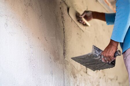 Construction workers are plastering the cement for building walls with plastering tools.の写真素材
