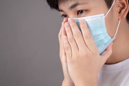 The sick person feels sick and coughs, ready to use their hands to cover their mouth and wear a virus mask on a gray background.
 New coronavirus 2019-nCoV .の写真素材