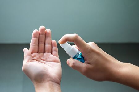 A close up of a person's hand is spraying alcohol with disinfecting hands to protect against bacteria and viruses, preventing health at home or at workの写真素材