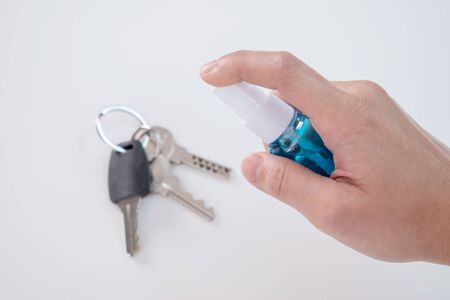 Close up of the hand with a spray of alcohol on the key to clean. Anti virus concept.