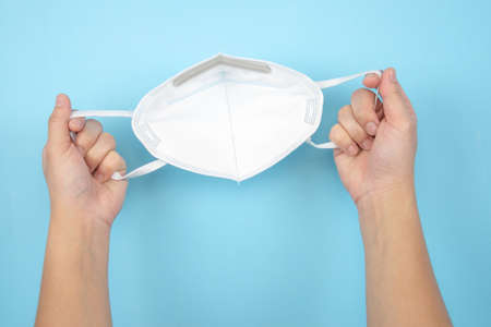Holding a protective mask on a blue background.