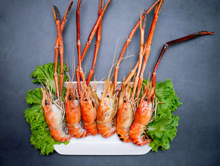 Top corner of freshly baked shrimp served on a plate with sauces, onions, garlic and chilies.