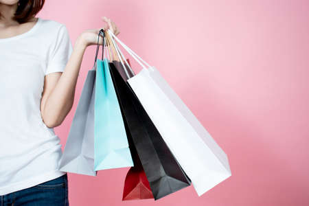 Happy Asian women carrying summer shopping bags on a pink background in the studio.の写真素材