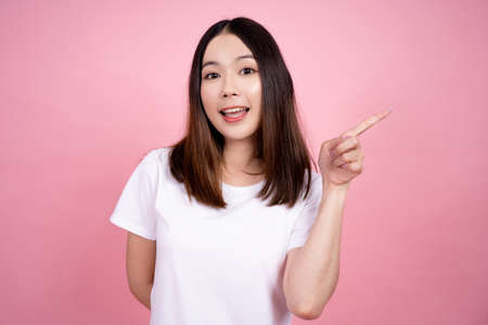 Asian woman pointing to the copy space, Pink background studio.の写真素材