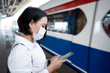 Asian woman wearing a mask waits on a subway train as a COVID-19 outbreak occurs in the country,...