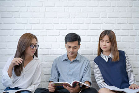A group of Asian students are brainstorming and reading books.