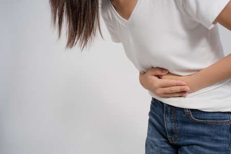 Pain in a waman's body. Asian woman has a stomachache on a white background.の写真素材