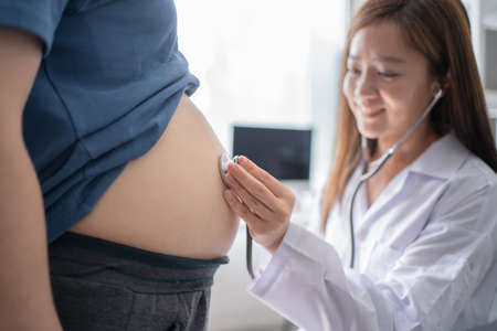 Female doctor uses a white stethoscope to examine pregnant women in the clinicの写真素材