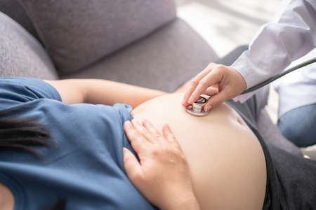 Asian doctor is examining the pregnant woman.の写真素材