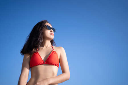 Portrait of a beautiful woman wearing a red bikini with a clear sky on vacation.の写真素材