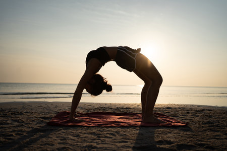 Woman training yoga on the beach at sunset in Thailand.の写真素材
