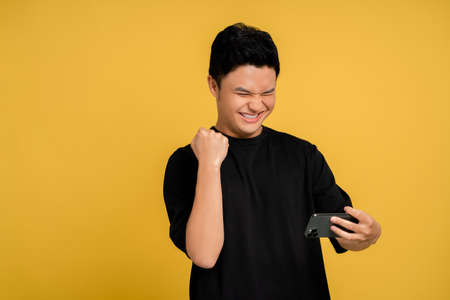 Happy smiling face of a young Asian man using a smartphone.の写真素材