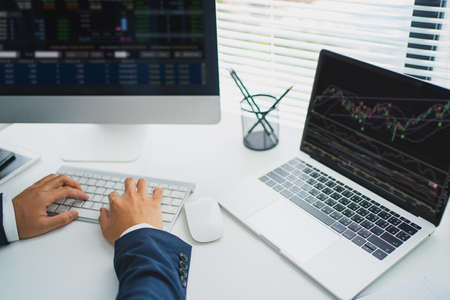 Young business man deal Investment stock market. He was using a laptop on the table. Trading Stock...