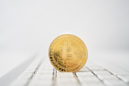 Golden bitcoin coin on laptop computer keyboard.