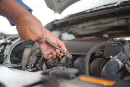 Maintenance concept. A close-up of a young auto mechanic repairing a car with a wrench.の写真素材