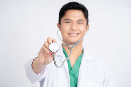 Close-up of Asian doctor's hand holding a stethoscope on white background.の写真素材