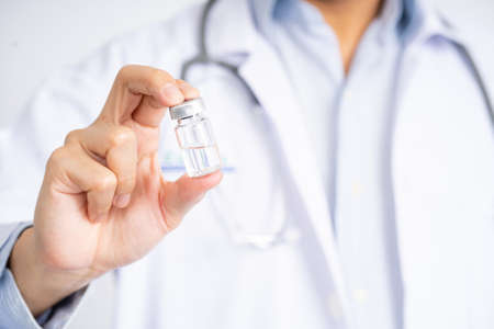 Close-up of a doctor's hand holding a bottle of covid-19 vaccine. Health and medical concepts.の写真素材