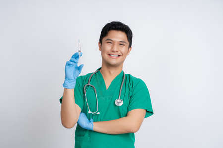Portrait of an Asian male doctor in uniform on isolated background. He was holding a syringe with an injection.の写真素材