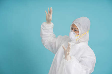 Doctor wearing white protective clothing shows shock in a light blue background studio. Isolated background.の写真素材