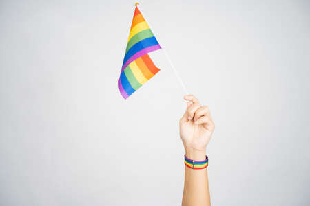 LGBT concept. Holding a rainbow flag on a white background. Isolated background.の写真素材