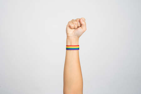 Close-up of young woman's hand wearing LGBTQ pride awareness wristband on white background on white background.の写真素材