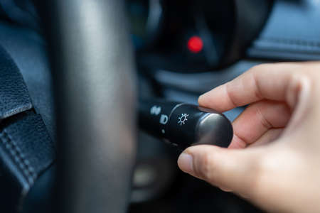 Hand adjusting car headlight control switch.