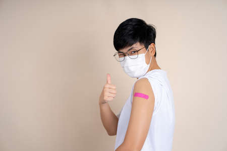 Asian people wearing a mask after shot receive covid-19 anti virus vaccine for the first time in campaign vaccination. On isolated background.の写真素材