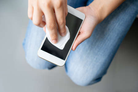 Cleaning the smartphone screen with a wet wipe to cleaning from dirt dust and other external factors, top view.の写真素材