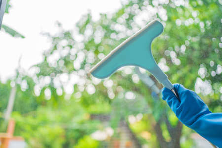Window cleaner for washing a windows. Hand in blue glove hold cleaning squeegee.の写真素材