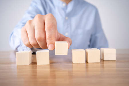 Hand holding blank wooden block cubes on table background, business concept background, mock up, template, bannerの写真素材