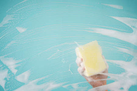 Hands are cleaning windows with sponge and detergent.の写真素材