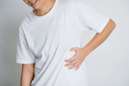 Asian people in a white t shirt on a white background hold hands on his stomach, liver pain,...