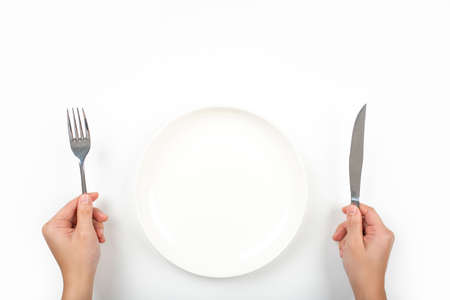 Woman with fork, knife and empty plate on on a on a white background, top view.