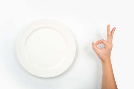 Plate and a woman hand showing OK sign, isolated on whiteの写真素材