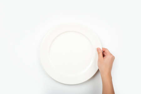 Woman with empty white circle plate on white background, top view. She is hungry.の写真素材