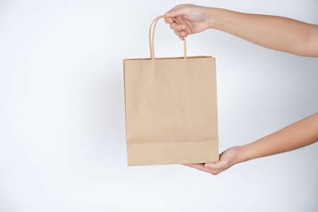 Reduce, Paper bag in male hands over grey background.