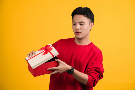 Side view, Handsome Asian man a look inside gift box, unpacking present to know what he received.の写真素材