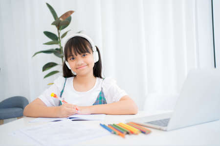 Cute little girl children using laptop computer, studying through online e-learning system.の写真素材