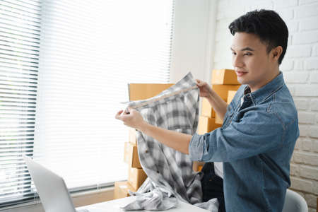 Handsome Asian businessman measuring shirt sizes for online orders for customers. Success in online shopping business.の写真素材