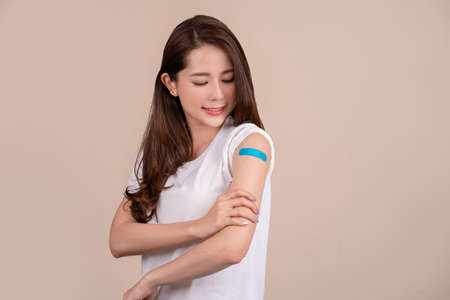 Happy asian woman showing arm after receiving vaccination. Vaccination.