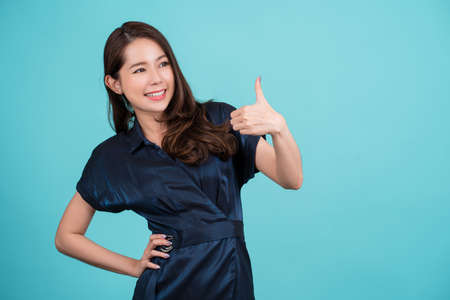 Smiling young Asian woman showing thumbs up isolated on a blue background