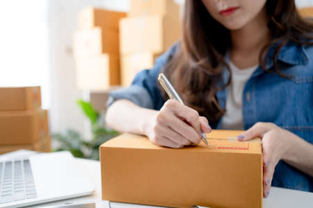 SME owners female entrepreneurs writing the address on receipt box and check online orders to prepare to pack the boxes. New normal concept.の写真素材
